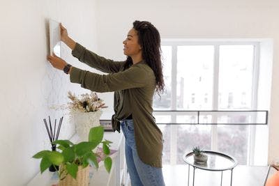 Woman hanging wall decor on wall