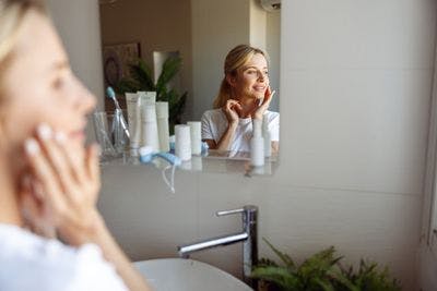 Reflection of woman doing skincare in the mirror